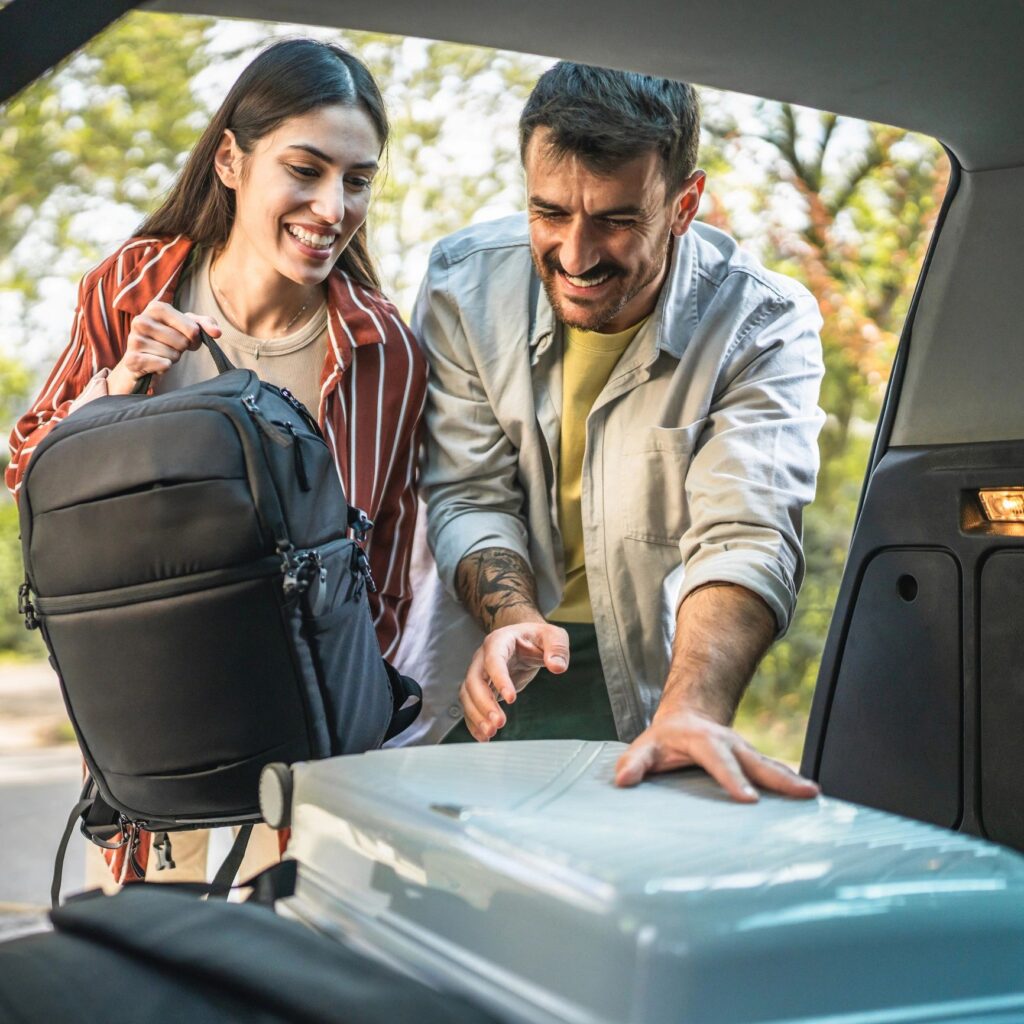 man and women couple pack luggage baggage in trunk of the car